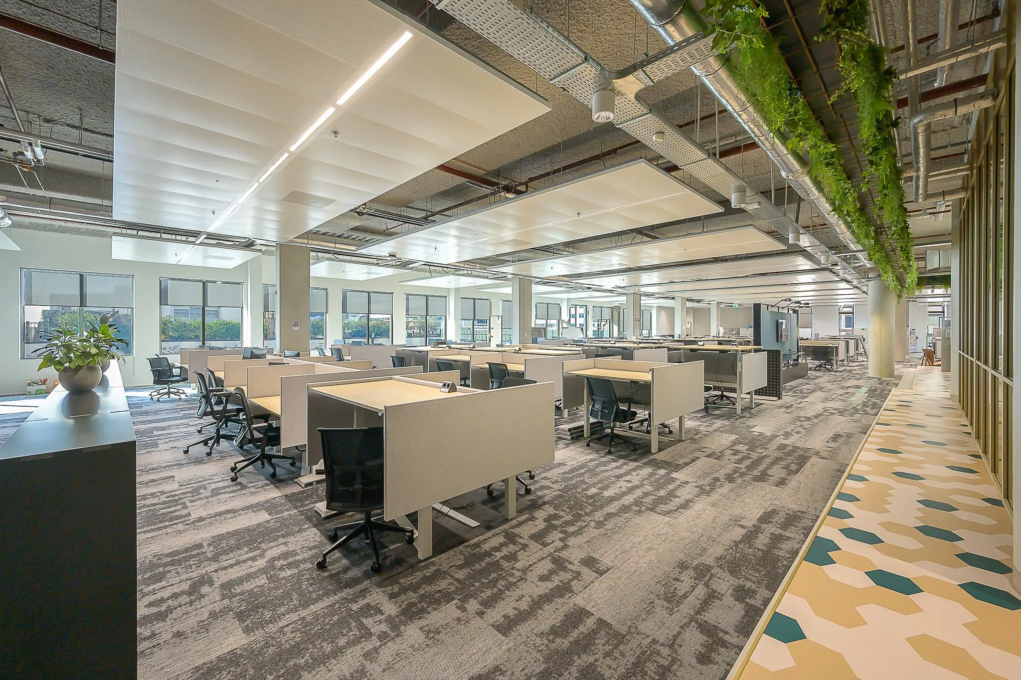 Modern, open kantoorinterieur aan de Coolsingel met werkplekken, veel daglicht en groene plafonddecoratie.