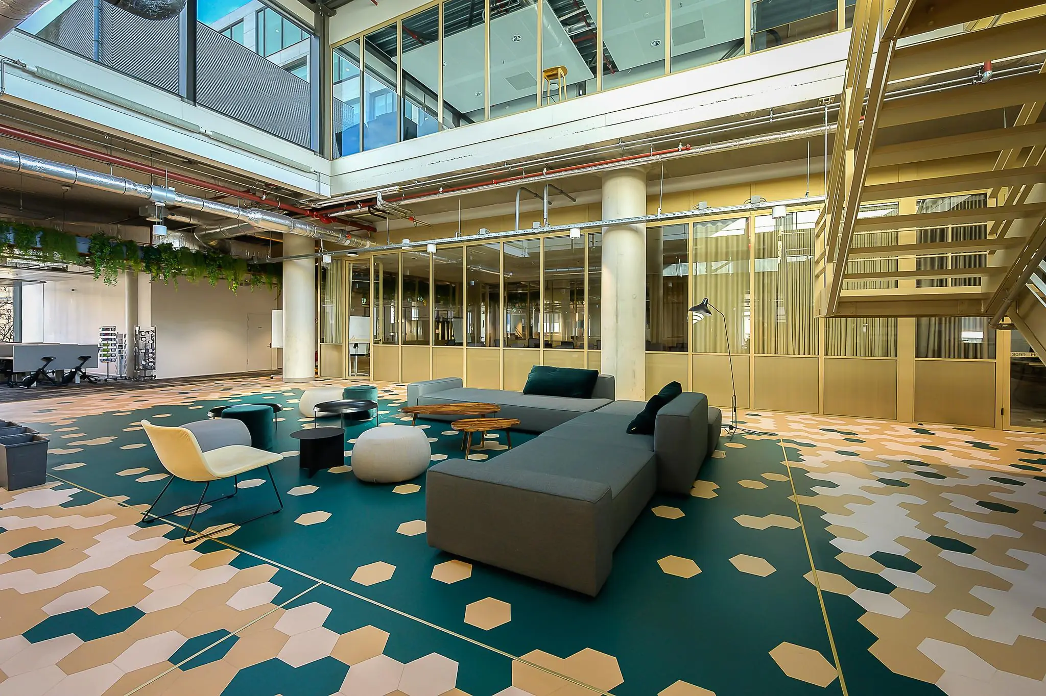 Moderne en open lounge- of werkruimte in het gebouw aan de Coolsingel, met kleurrijke geometrische vloer, designmeubilair en glazen wanden.