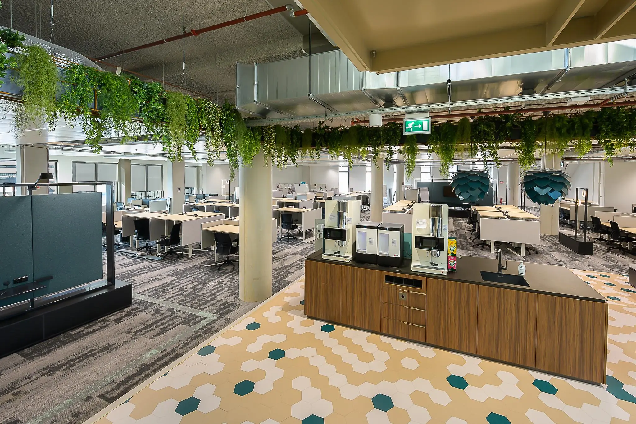 Modern kantoorinterieur aan de Coolsingel met flexwerkplekken, een koffiecorner en hangende planten.