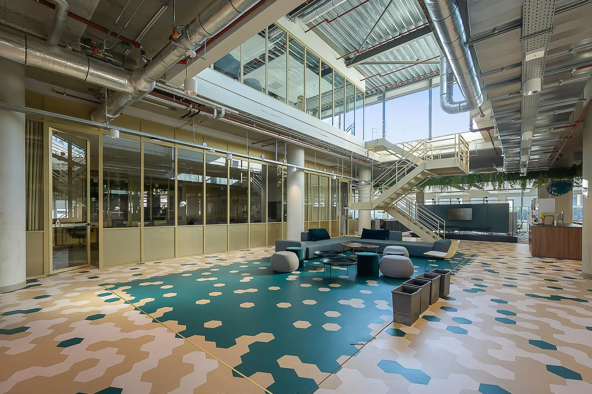 Moderne kantoorlobby aan de Coolsingel met kleurrijke vloer, glazen vergaderruimtes en een open trap naar de bovenverdieping.