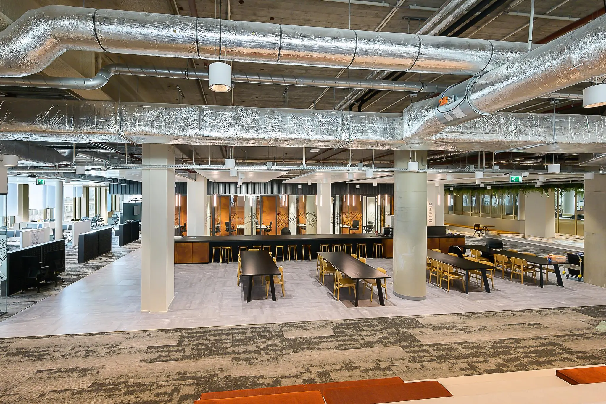 Moderne kantoorruimte aan de Coolsingel met open werkplekken, vergaderruimtes en een gemeenschappelijke zithoek.