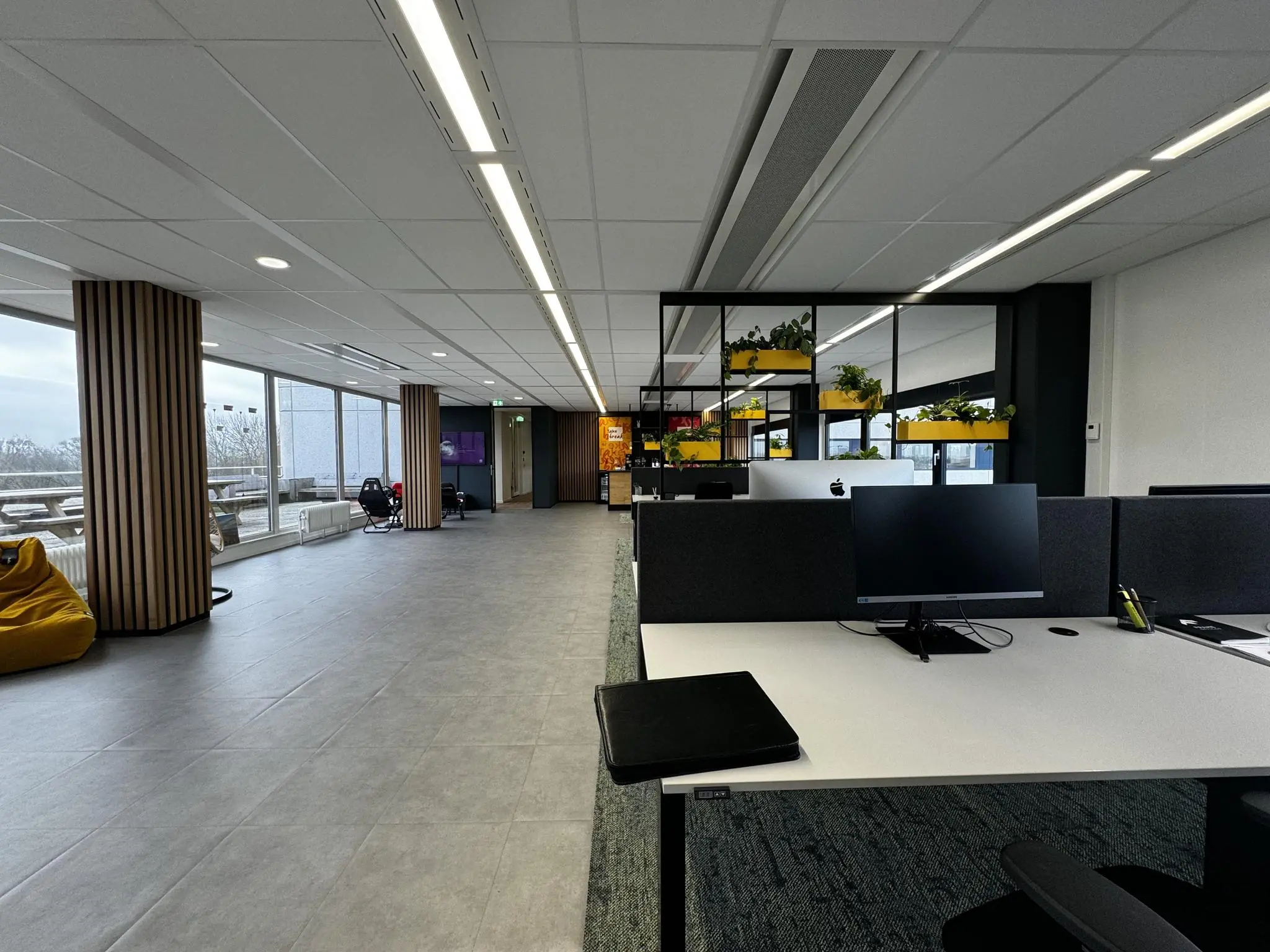 Modern kantoorinterieur op Rijnzathe met open werkplekken, planten en een zithoek bij de ramen.