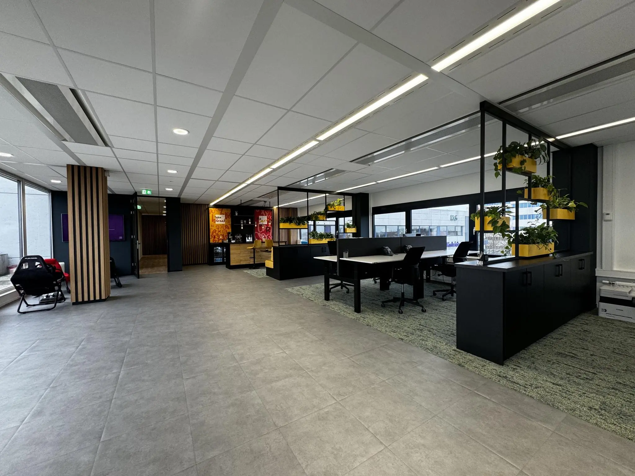 Moderne open kantoorruimte in Rijnzathe met werkplekken, planten en een koffiecorner.