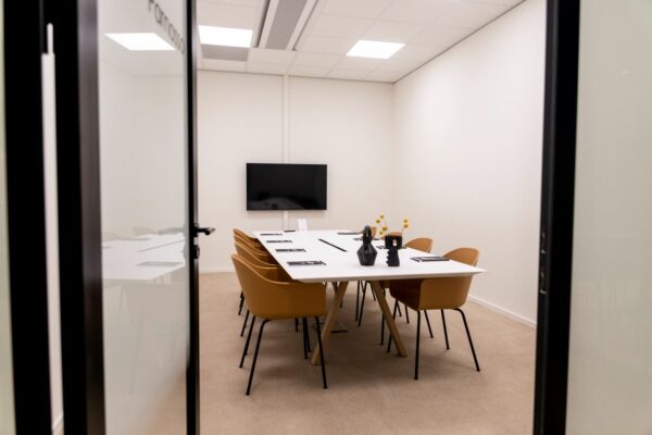 Vergaderruimte Rijnzathe met een lange tafel, acht stoelen, een flatscreen en moderne decoratie.