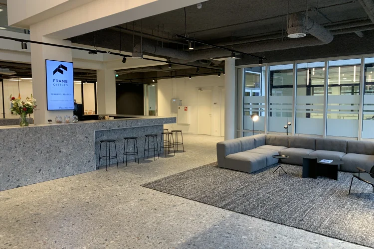 Moderne ontvangsthal van Frame Offices Rijnzathe met een balie, zitgedeelte en strakke inrichting.