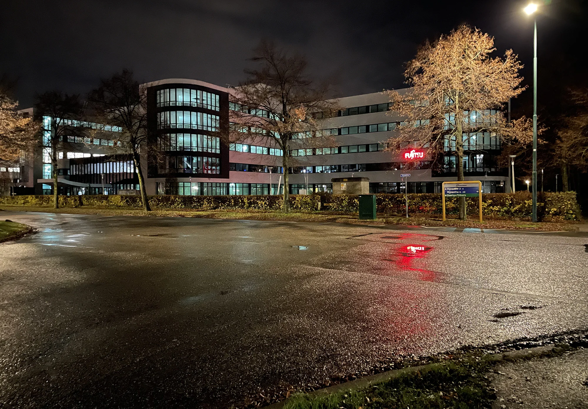 Kantoorgebouw aan de Rijnzathe in De Meern met verlichte Fujitsu-logo's in de avond.