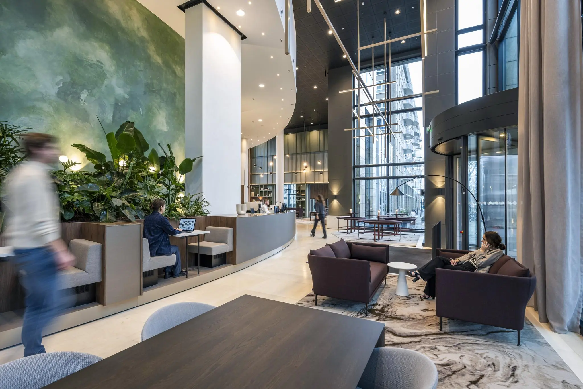 Moderne lobby van kantoorgebouw Amstelplein met zithoeken, werkplekken en hoge ramen.