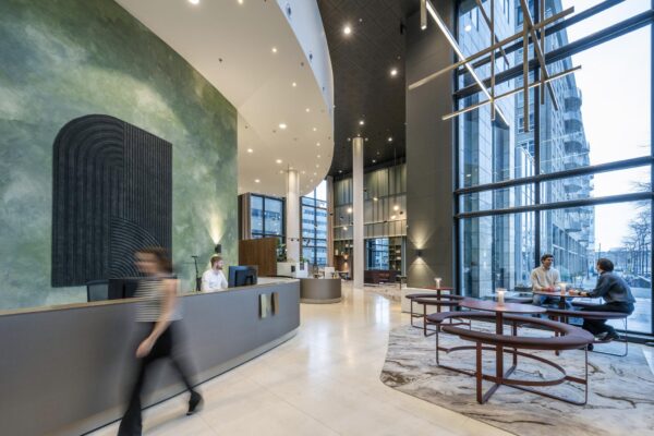 Moderne ontvangsthal van kantoorgebouw Amstelplein met receptiebalie, zitgedeelte en hoge glazen gevel.