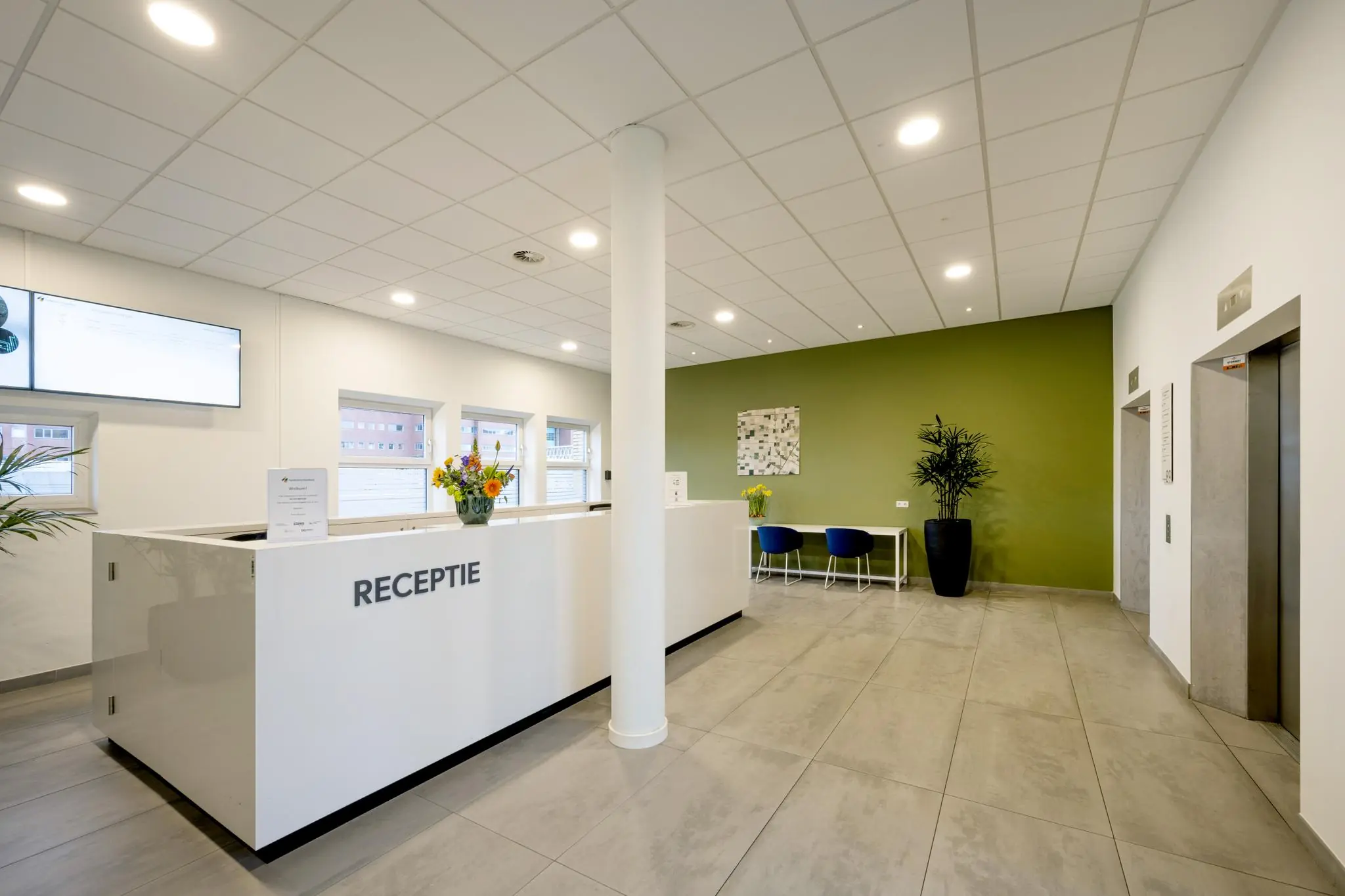 Moderne wachtruimte met receptiebalie, zitgedeelte en twee liften aan het Stationsplein.
