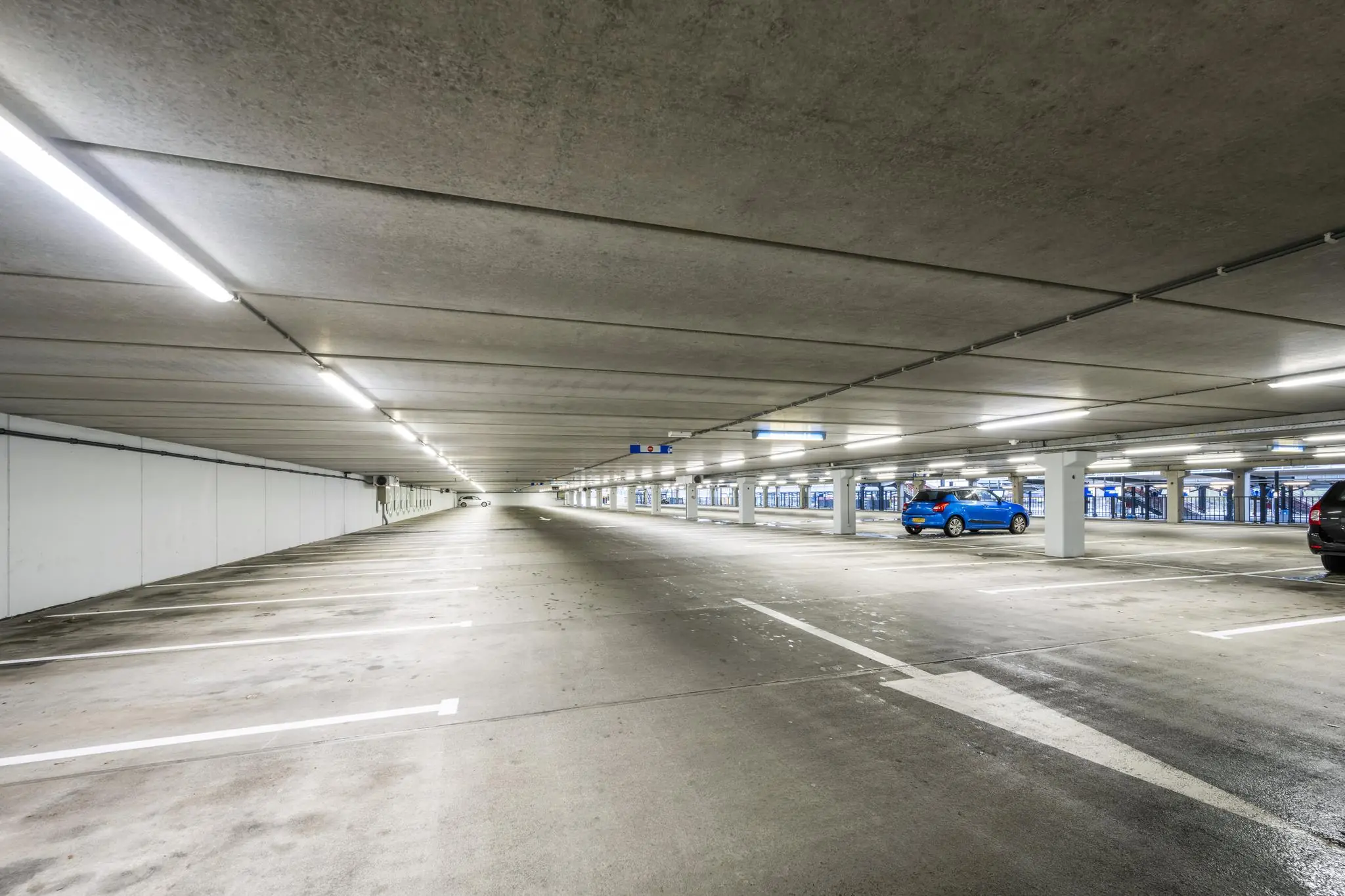 Overdekte parkeergarage bij Stationsplein met enkele geparkeerde auto's en lege parkeerplaatsen.