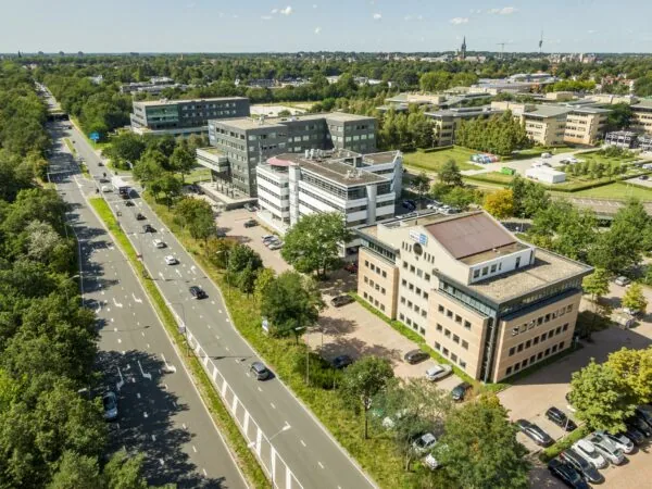 Luchtfoto van kantorencomplex Marathon in een groene stadsomgeving met aangrenzende verkeersweg.