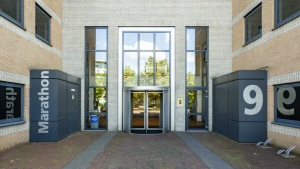 Ingang van het kantoorgebouw Marathon met huisnummer 9 en een draaideur tussen hoge ramen.