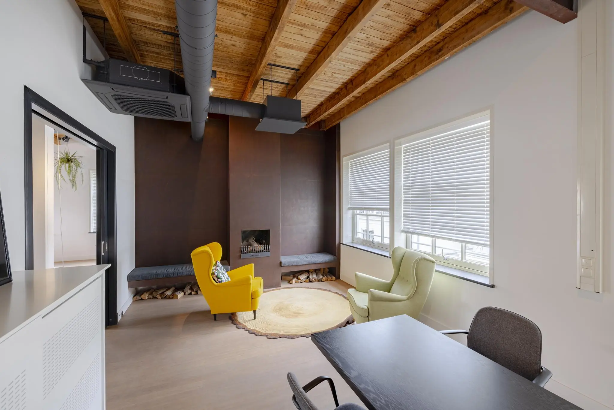 Modern ingerichte vergaderruimte aan de Plantage Middenlaan met houten plafond, kleurrijke fauteuils en een ingebouwde haard.