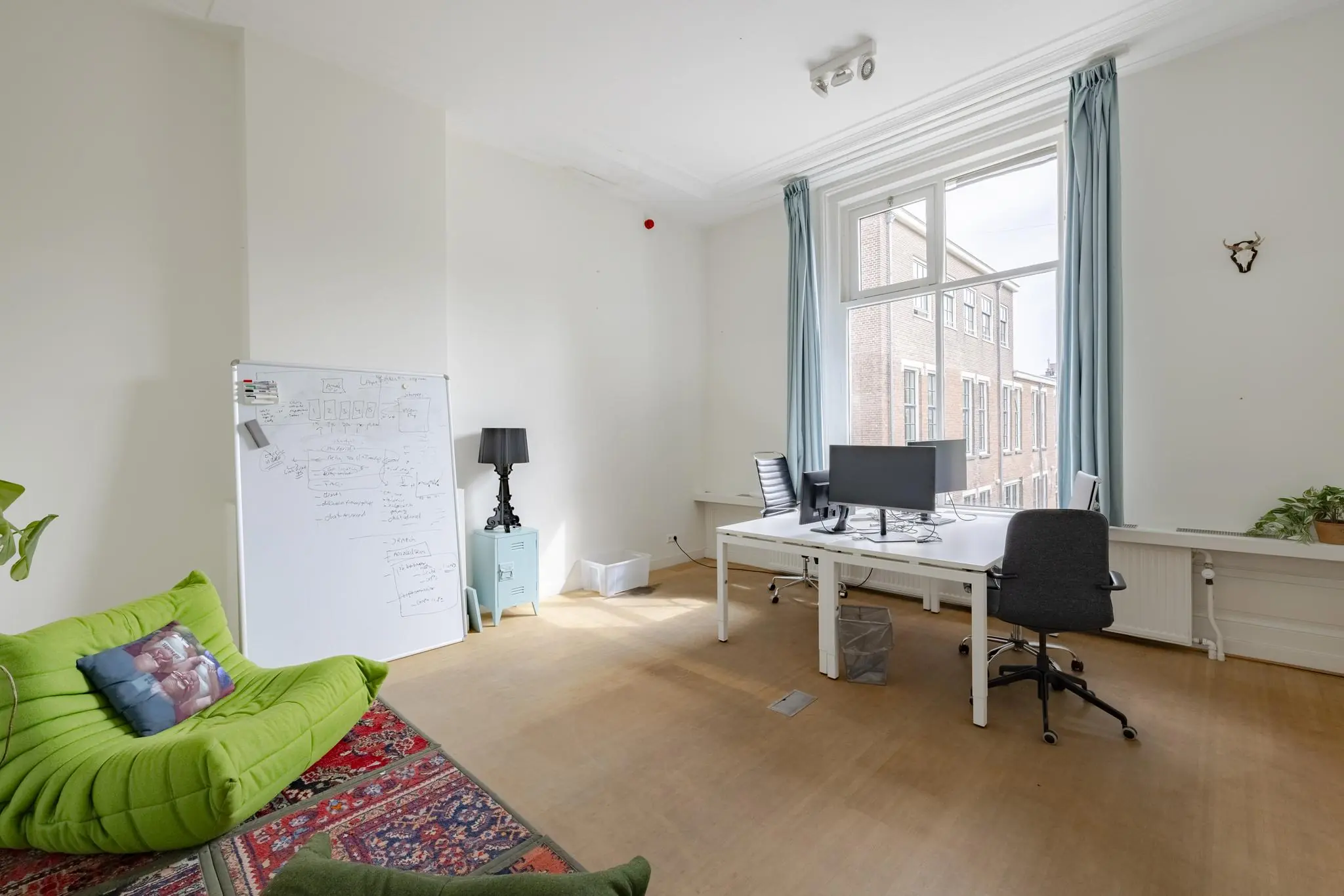 Licht en modern kantoor aan de Plantage Middenlaan met bureaus, whiteboard en loungehoek.