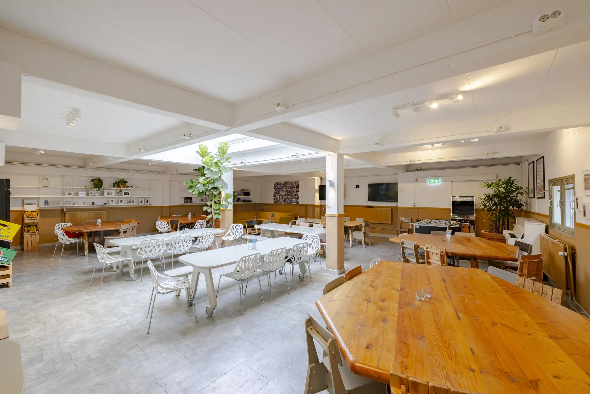 Ruime, lichte kantine aan de Plantage Middenlaan met houten en witte tafels, moderne stoelen en veel groen.