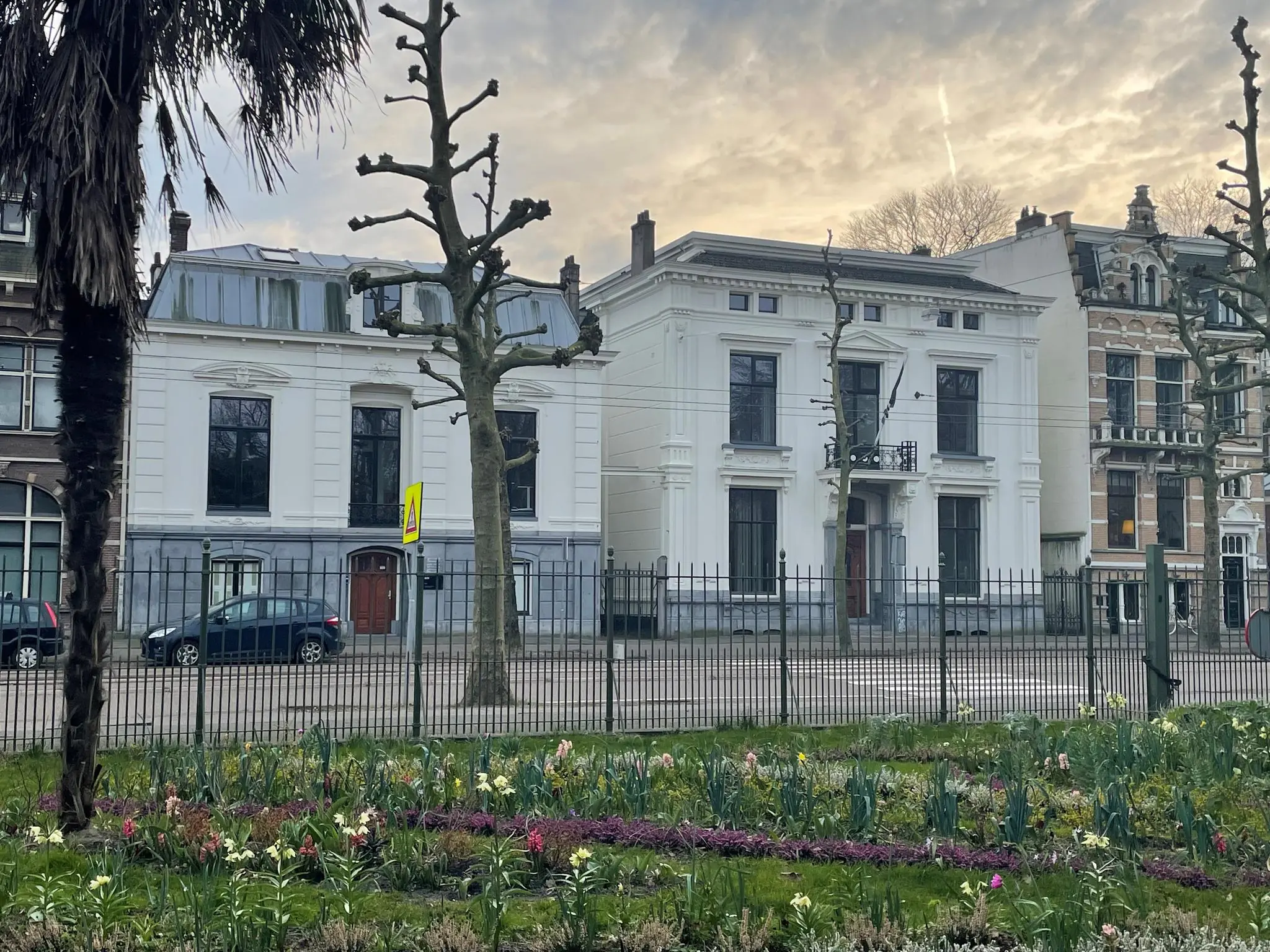 Witte herenhuizen aan de Plantage Middenlaan in Amsterdam met bloeiende voorjaarsbloemen op de voorgrond.