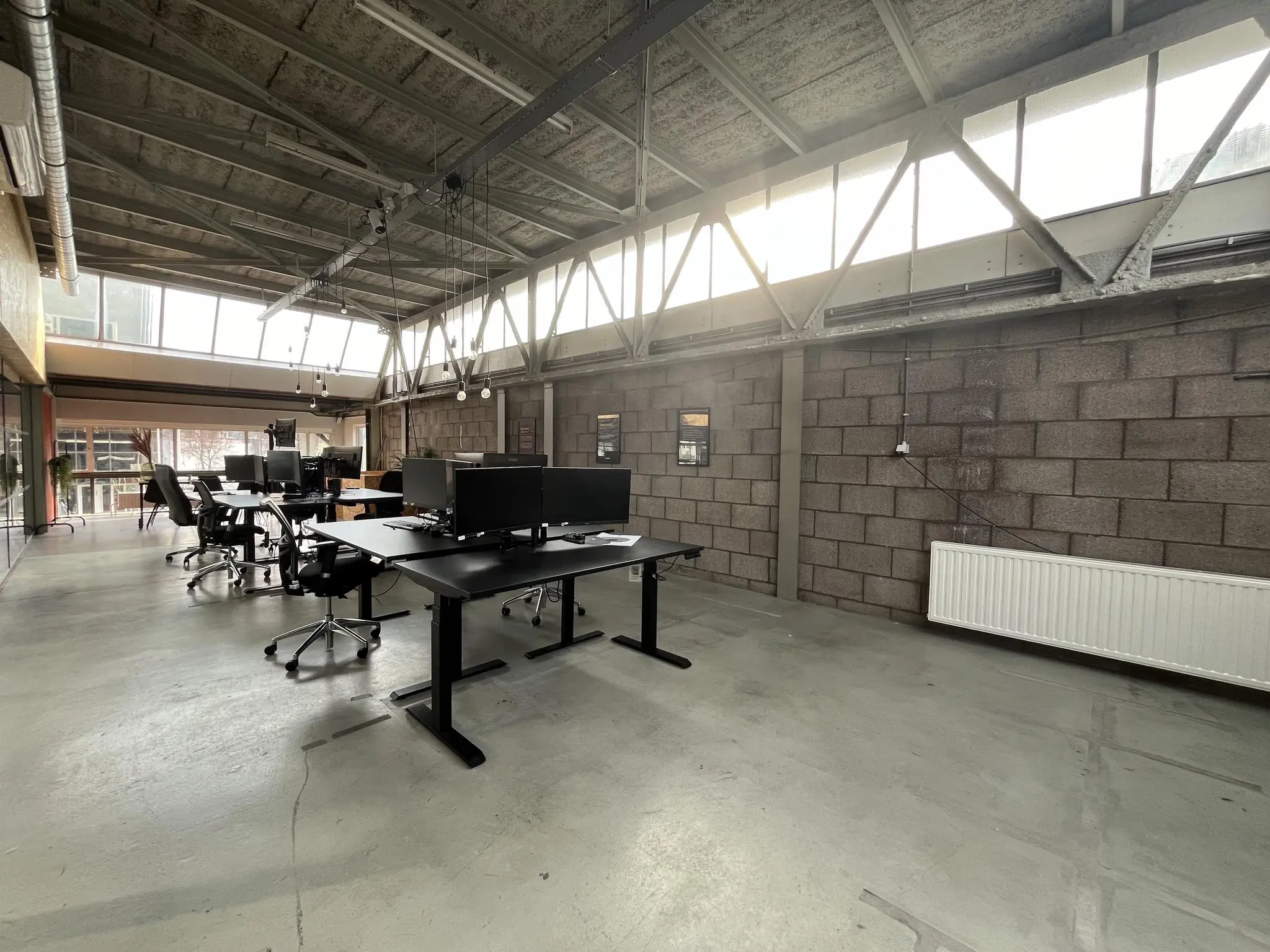 Modern industrieel kantoorinterieur aan de Eendrachtlaan met open werkplekken en grote ramen voor natuurlijk licht.