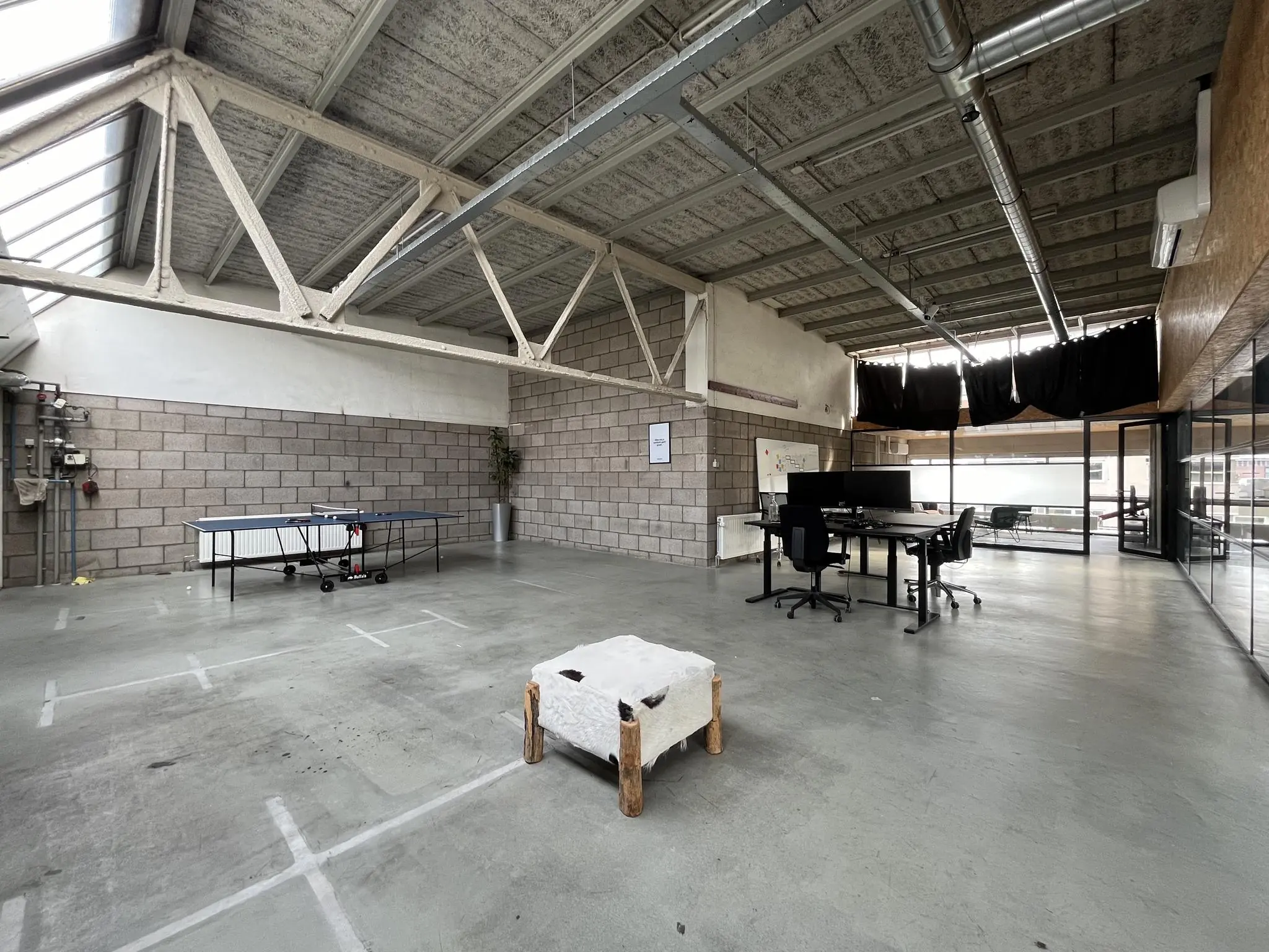 Ruime, industriële kantoorruimte aan de Eendrachtlaan met betonnen vloer, werkplekken en een tafeltennistafel.