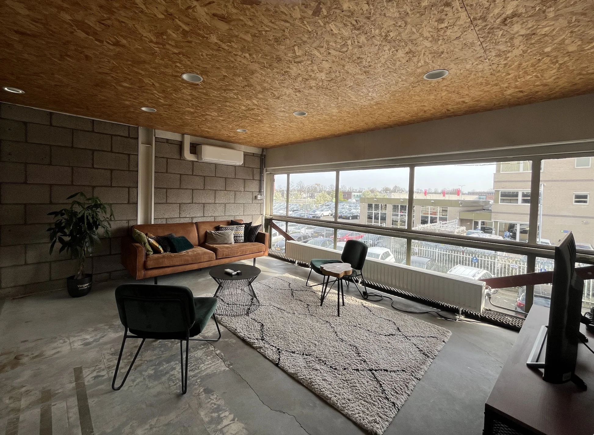 Moderne kantoorruimte aan de Eendrachtlaan met industriële inrichting, grote ramen en uitzicht op een parkeerterrein.