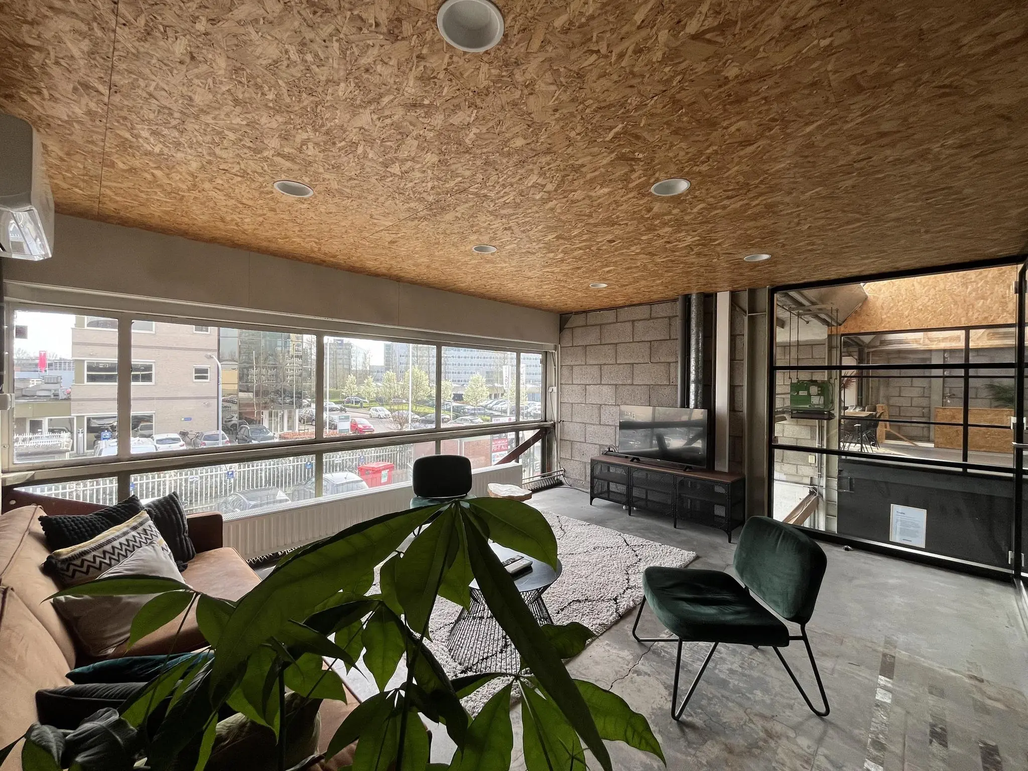 Moderne, industrieel ingerichte loungeruimte aan de Eendrachtlaan met grote ramen en uitzicht op een kantoorgebied.
