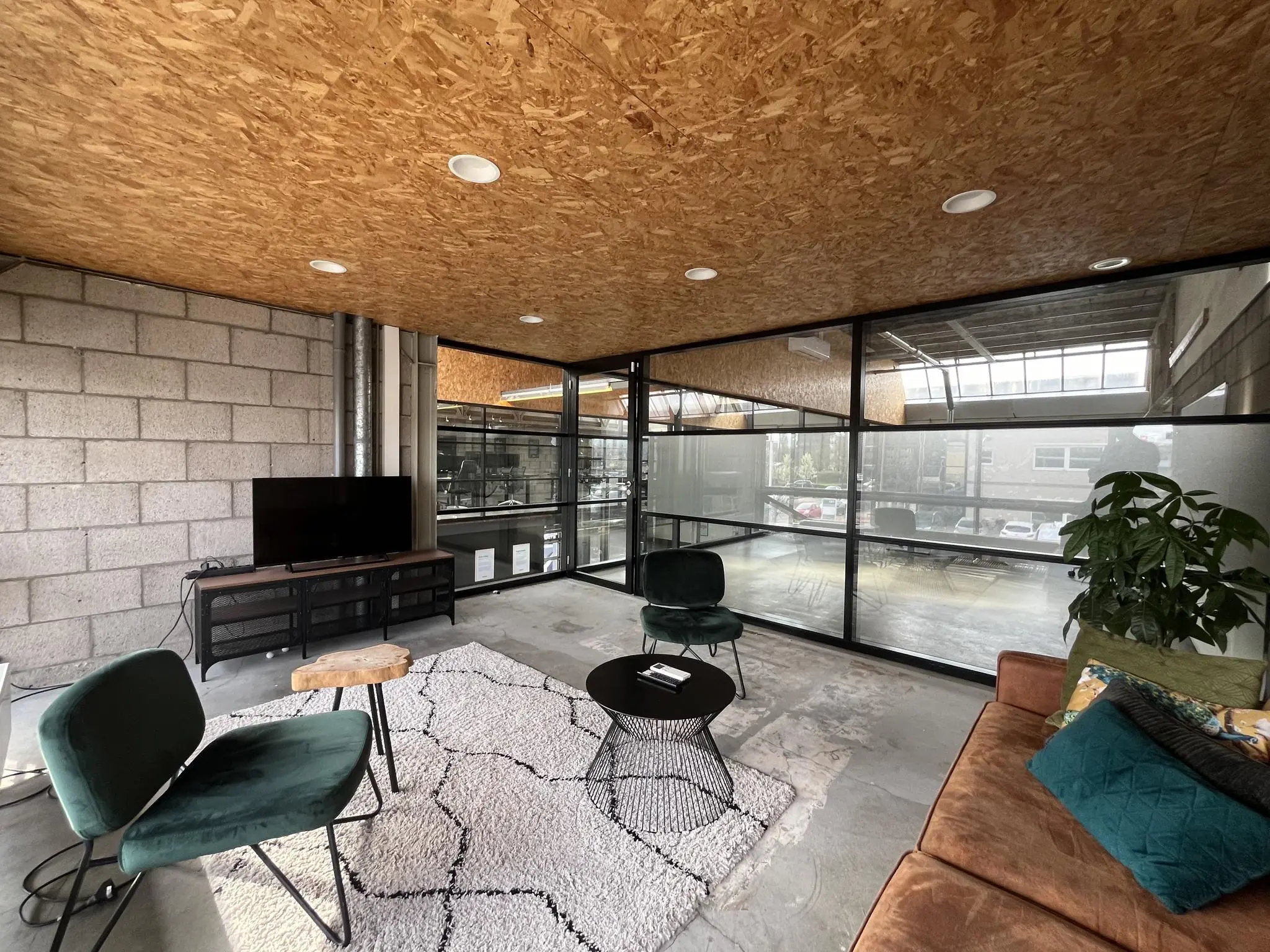 Moderne wachtruimte aan de Eendrachtlaan met een industriële inrichting, glazen wanden en comfortabele zithoek.