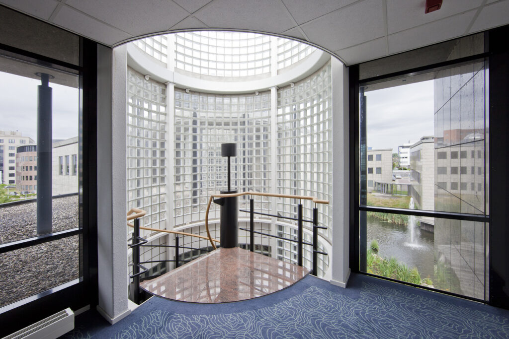 Modern trappenhuis met glazen bouwstenen en uitzicht op kantoorpanden aan de Rivium 1e Straat.