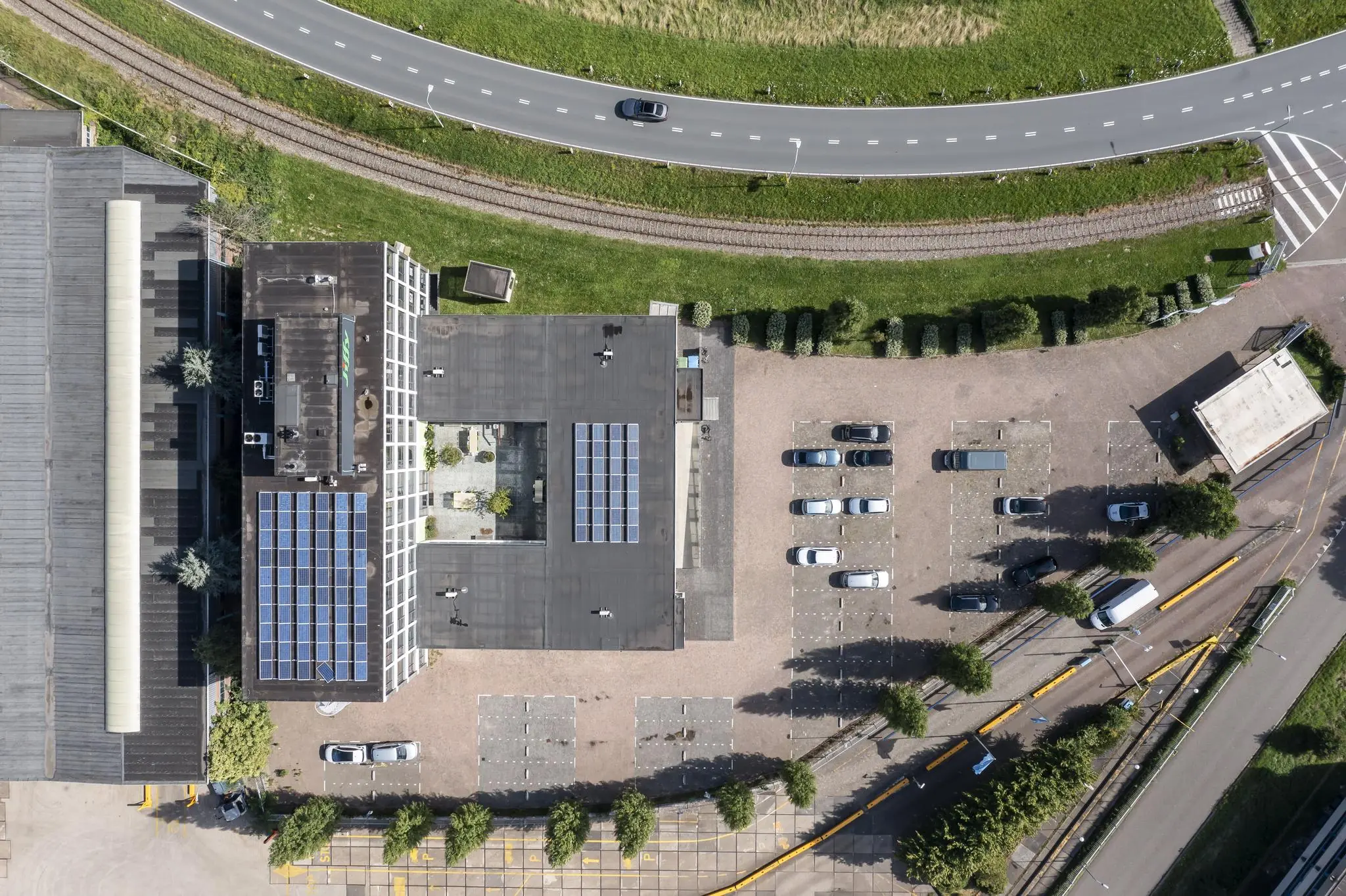 Luchtfoto van een kantoorgebouw aan de Lindtsedijk met zonnepanelen op het dak en een aangrenzend parkeerterrein.