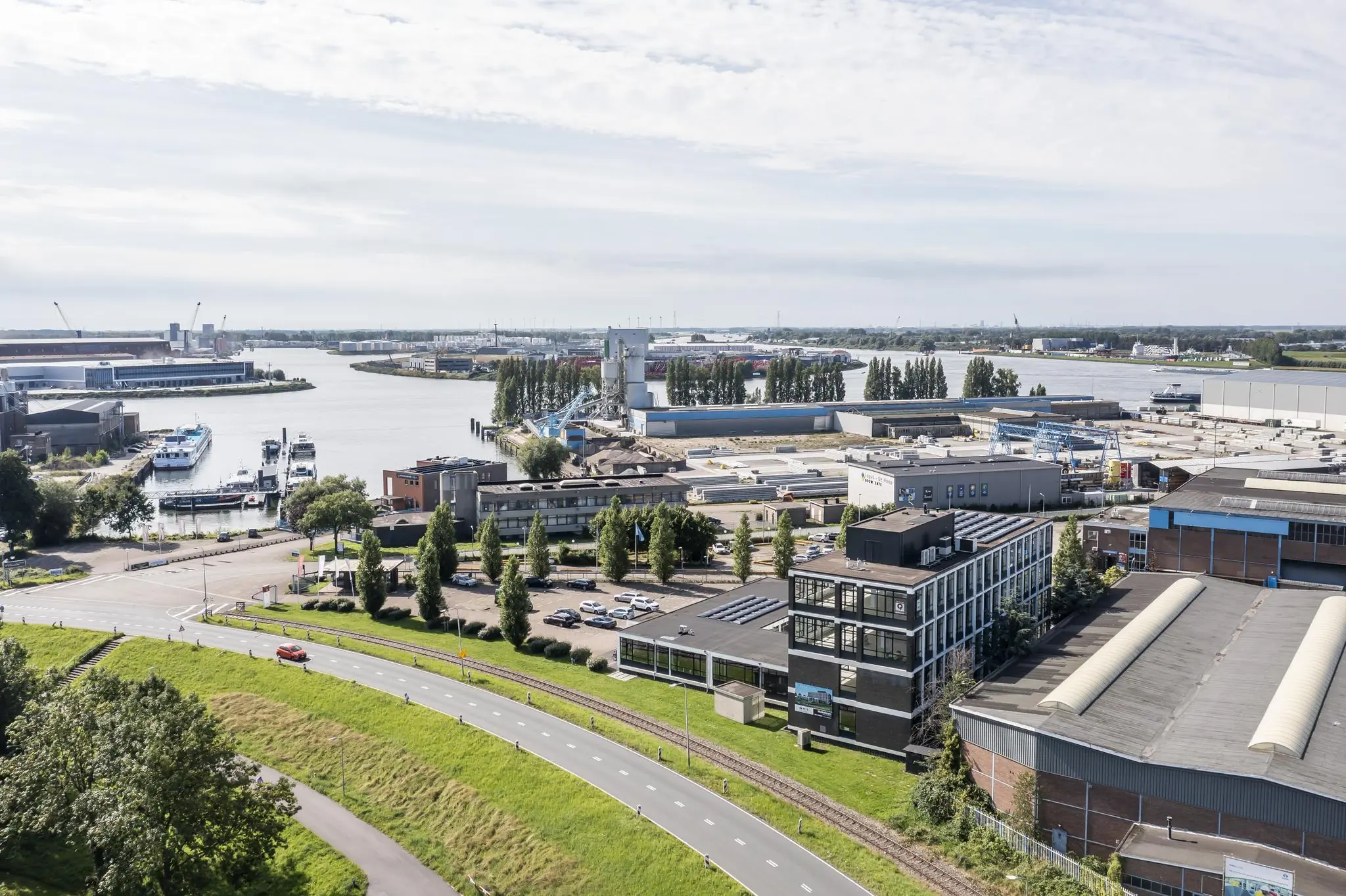 Luchtfoto van het industrieterrein aan de Lindtsedijk in Zwijndrecht met uitzicht op de rivier en havengebied.