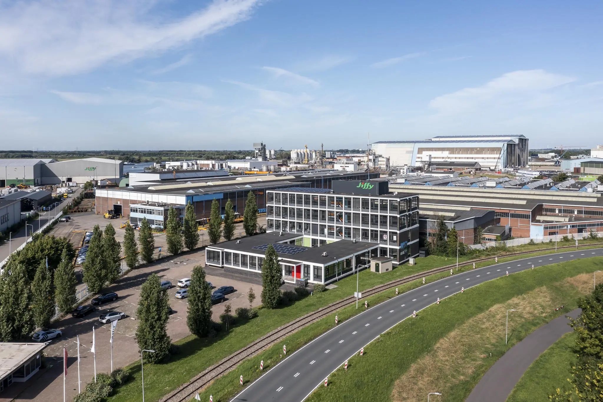 Luchtfoto van een industrieterrein aan de Lindtsedijk met prominente kantoorgebouwen, waaronder dat van Jiffy, en een weg op de voorgrond.