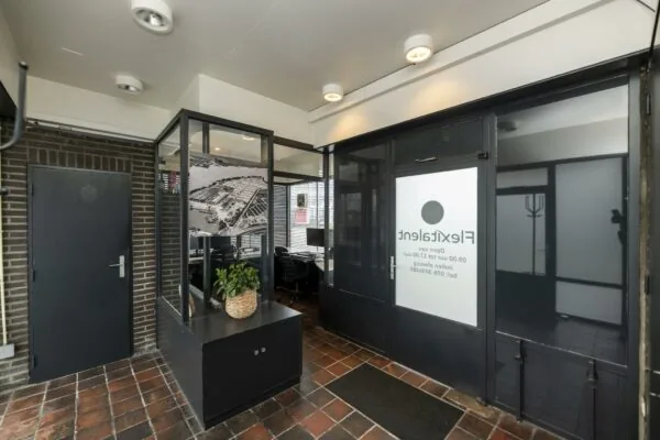 Ingang van een kantoorpand aan de Lindtsedijk met glazen wanden, een zwart-witte luchtfoto en het logo van FlexTalent op de deur.