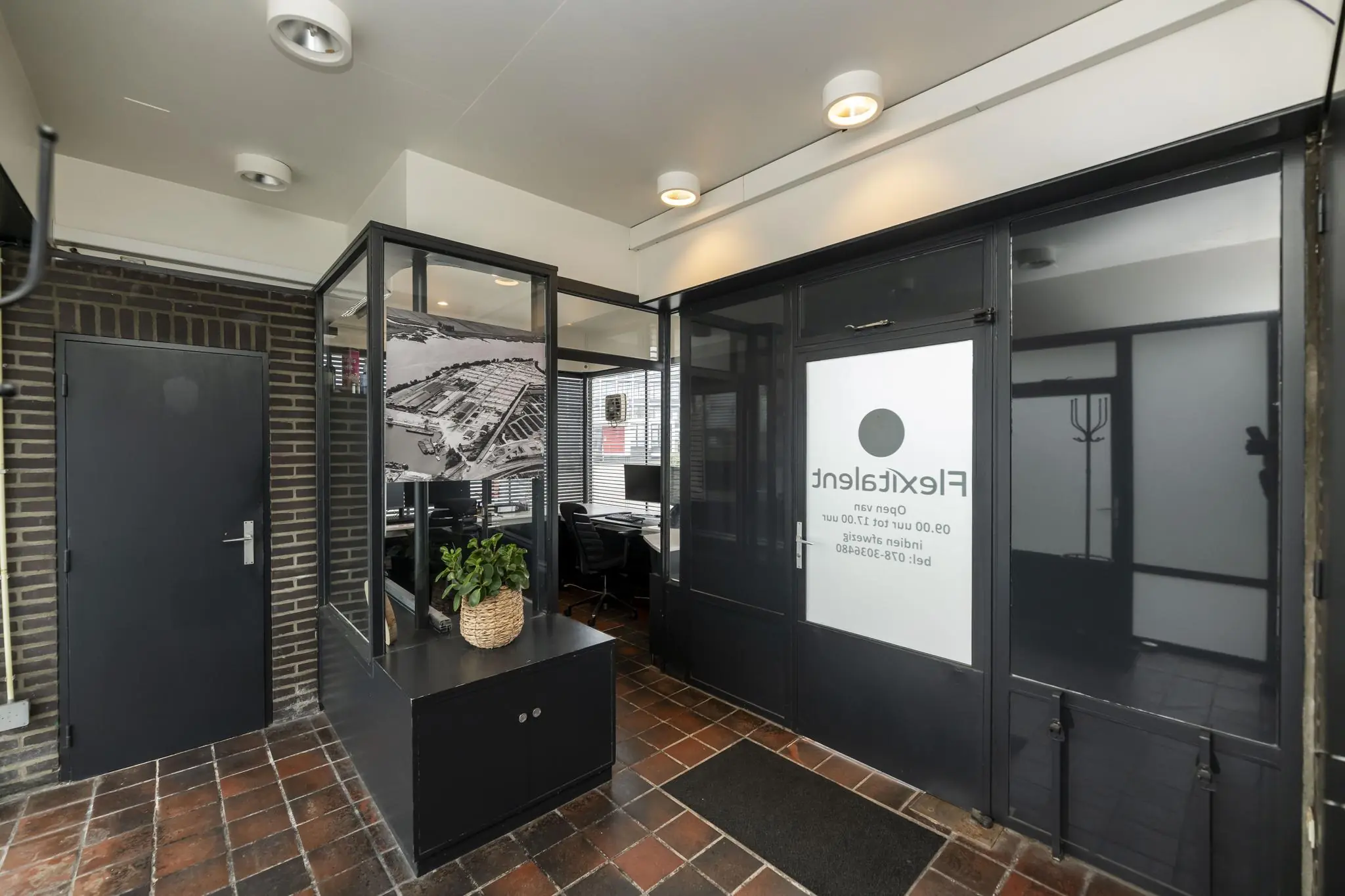 Ingang van een kantoorpand aan de Lindtsedijk met glazen wanden, een zwart-witte luchtfoto en het logo van FlexTalent op de deur.