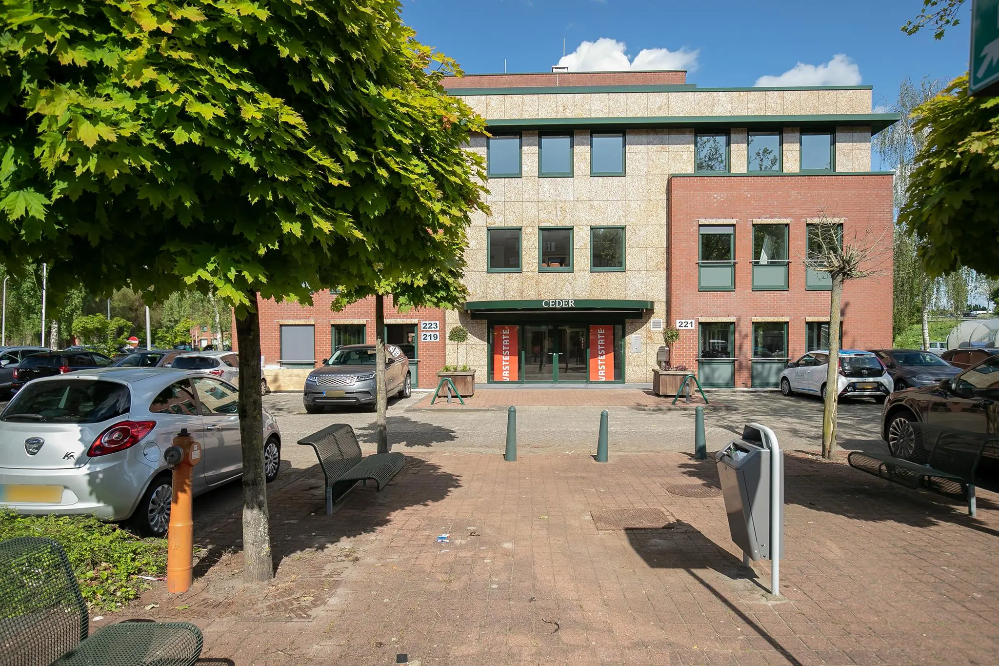 Voorgevel van kantoorgebouw 'CEDER' aan de Kralingseweg, met geparkeerde auto's en bomen op de voorgrond.