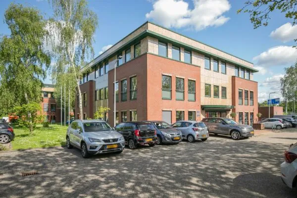 Modern kantoorgebouw aan de Kralingseweg met geparkeerde auto's op de parkeerplaats op een zonnige dag.