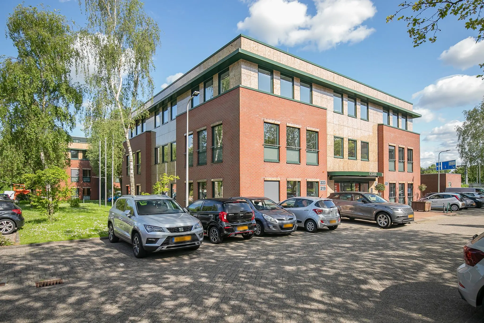 Modern kantoorgebouw aan de Kralingseweg met geparkeerde auto's op de parkeerplaats op een zonnige dag.
