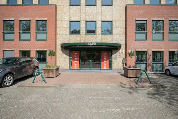 Vooraanzicht van het kantoorgebouw 'CEDER' aan de Kralingseweg 221 met entree en geparkeerde auto's.