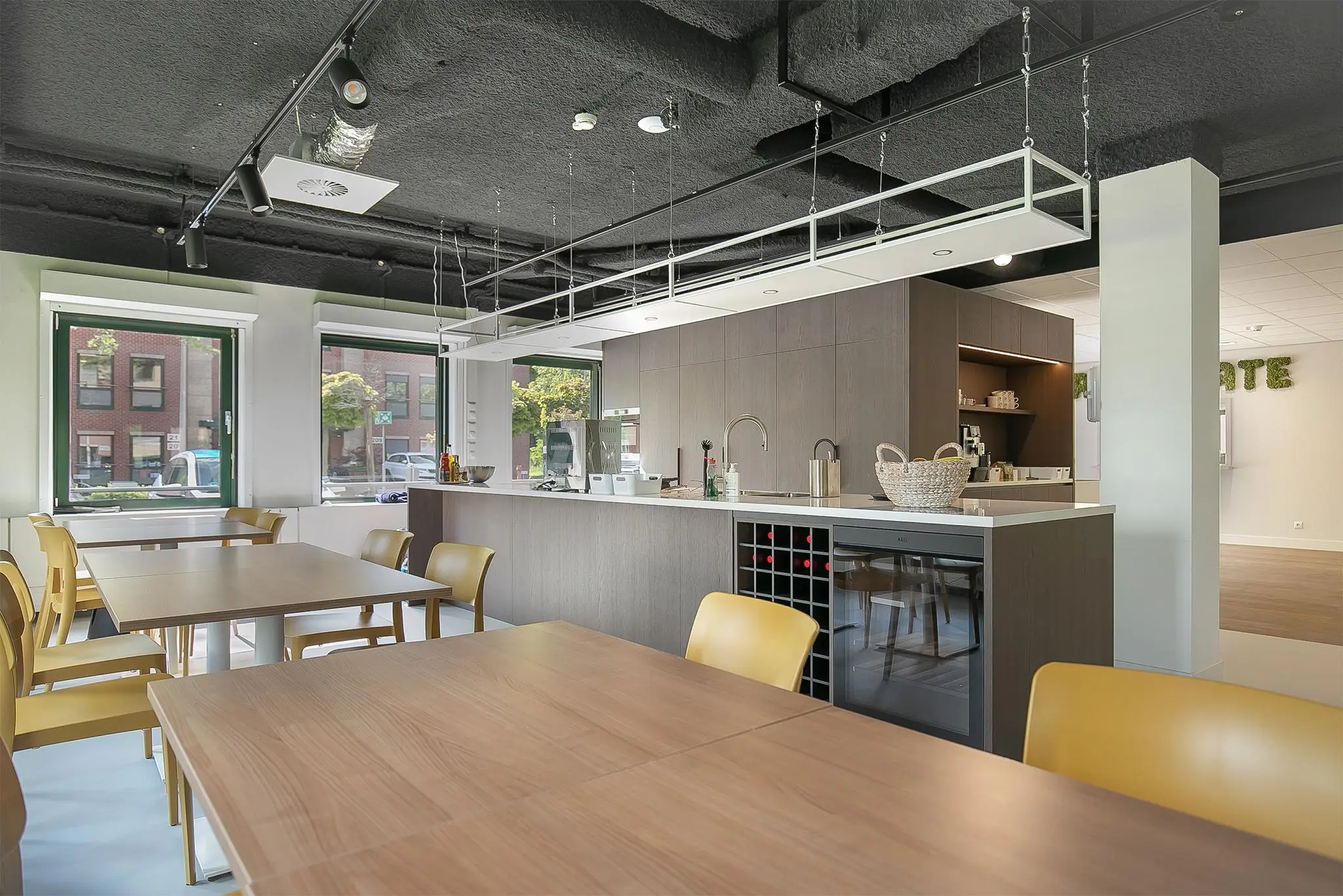 Moderne gemeenschappelijke keuken met eetgedeelte aan de Kralingseweg, voorzien van houten tafels, gele stoelen en ingebouwde apparatuur.