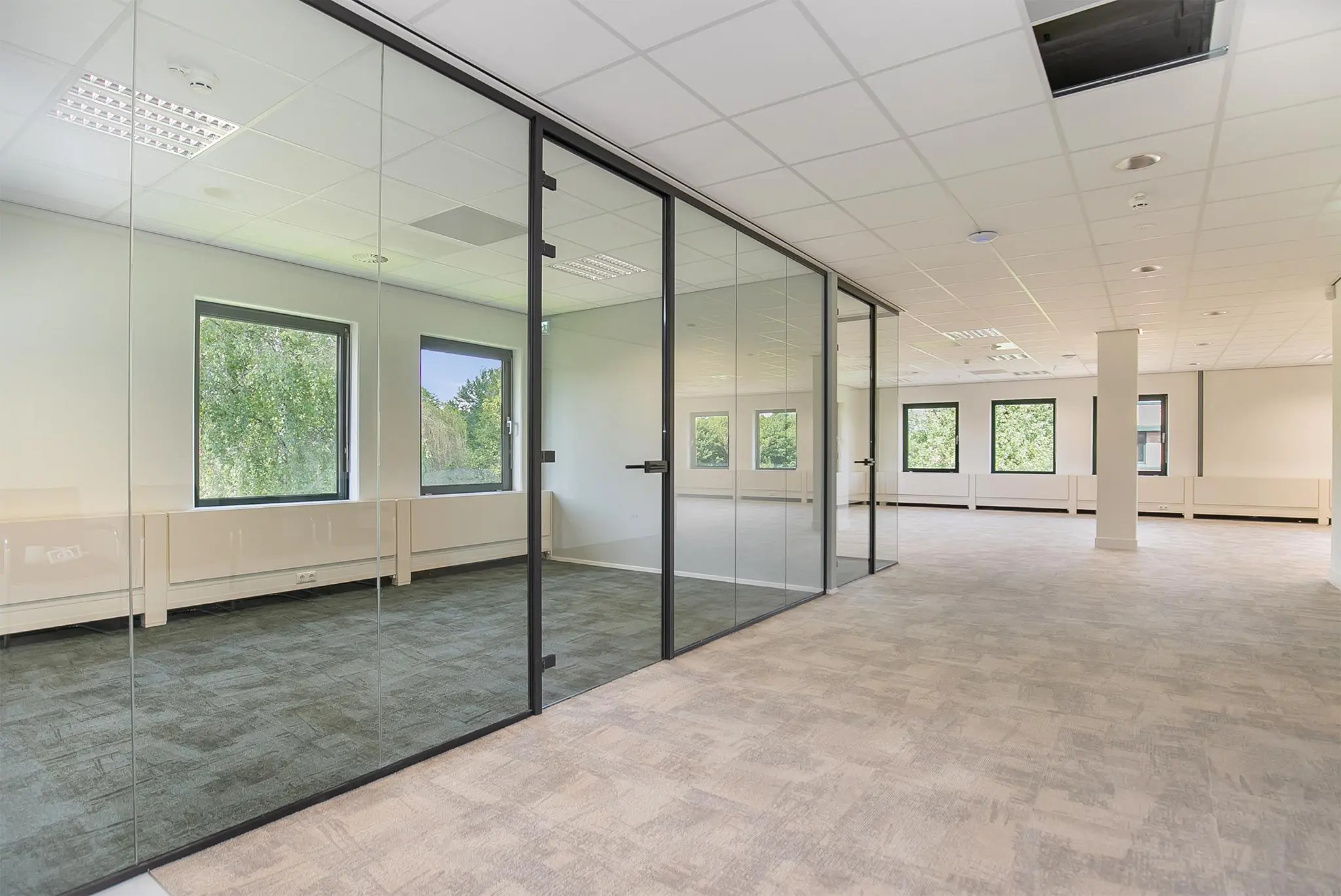 Moderne, lichte kantoorruimte aan de Kralingseweg met glazen scheidingswanden en uitzicht op groen.