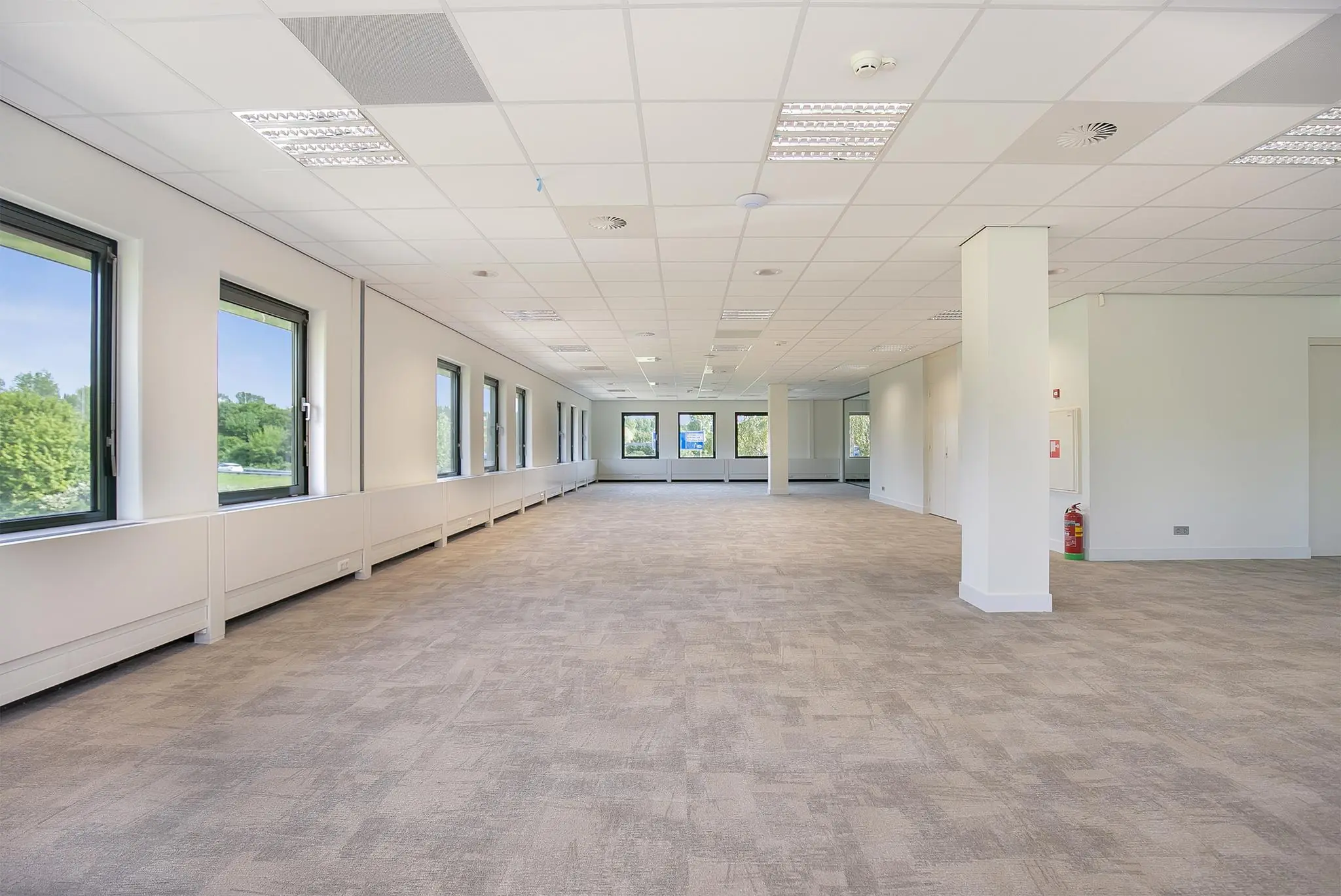 Licht en ruim leeg kantoorpand aan de Kralingseweg met grote ramen en systeemplafond.