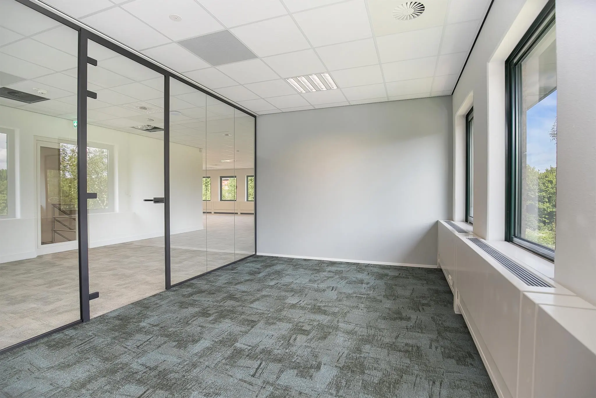 Licht en modern kantoorinterieur aan de Kralingseweg met glazen scheidingswand en grote ramen.
