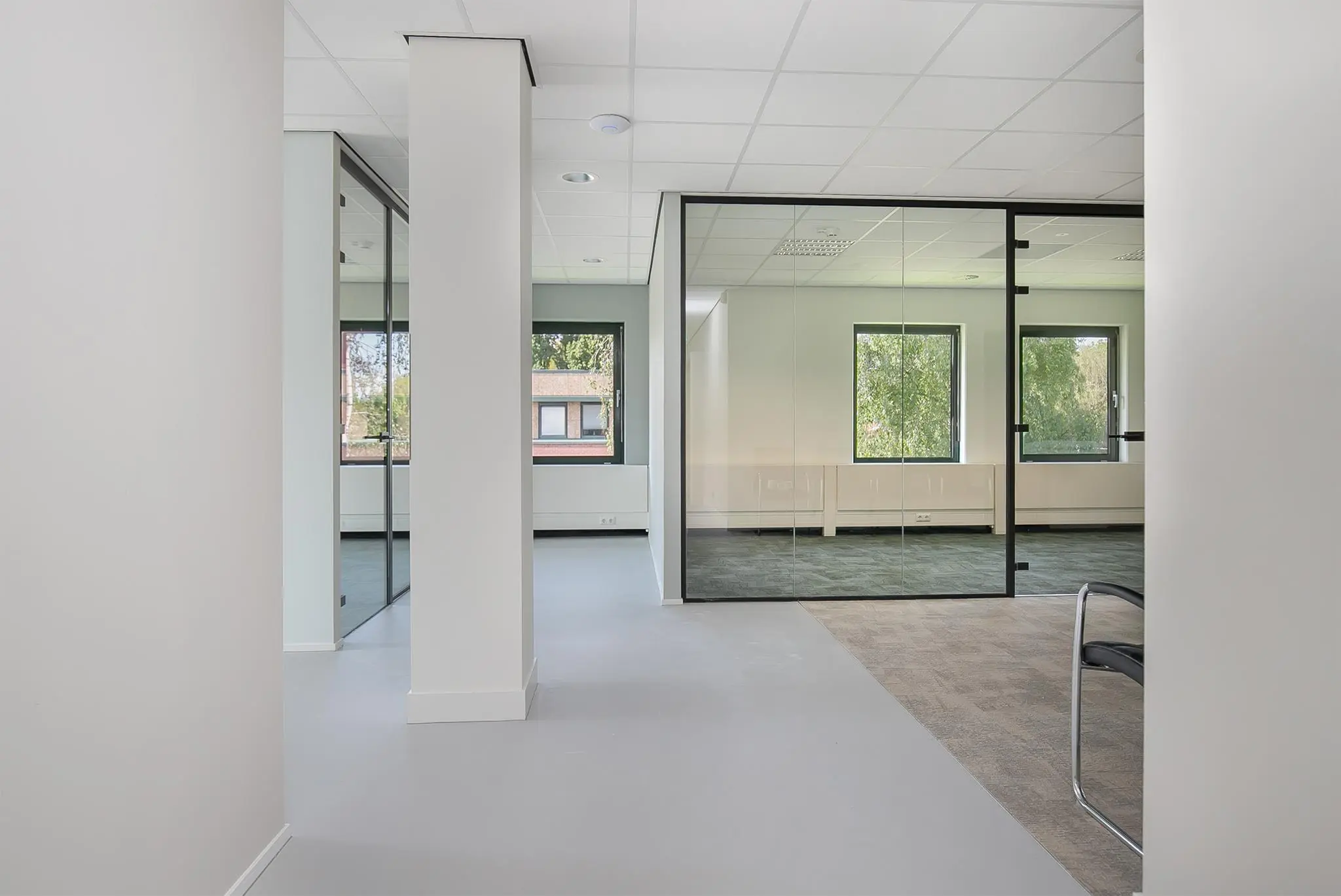 Moderne en lichte kantoorruimte aan de Kralingseweg met glazen wanden en uitzicht op groene omgeving.