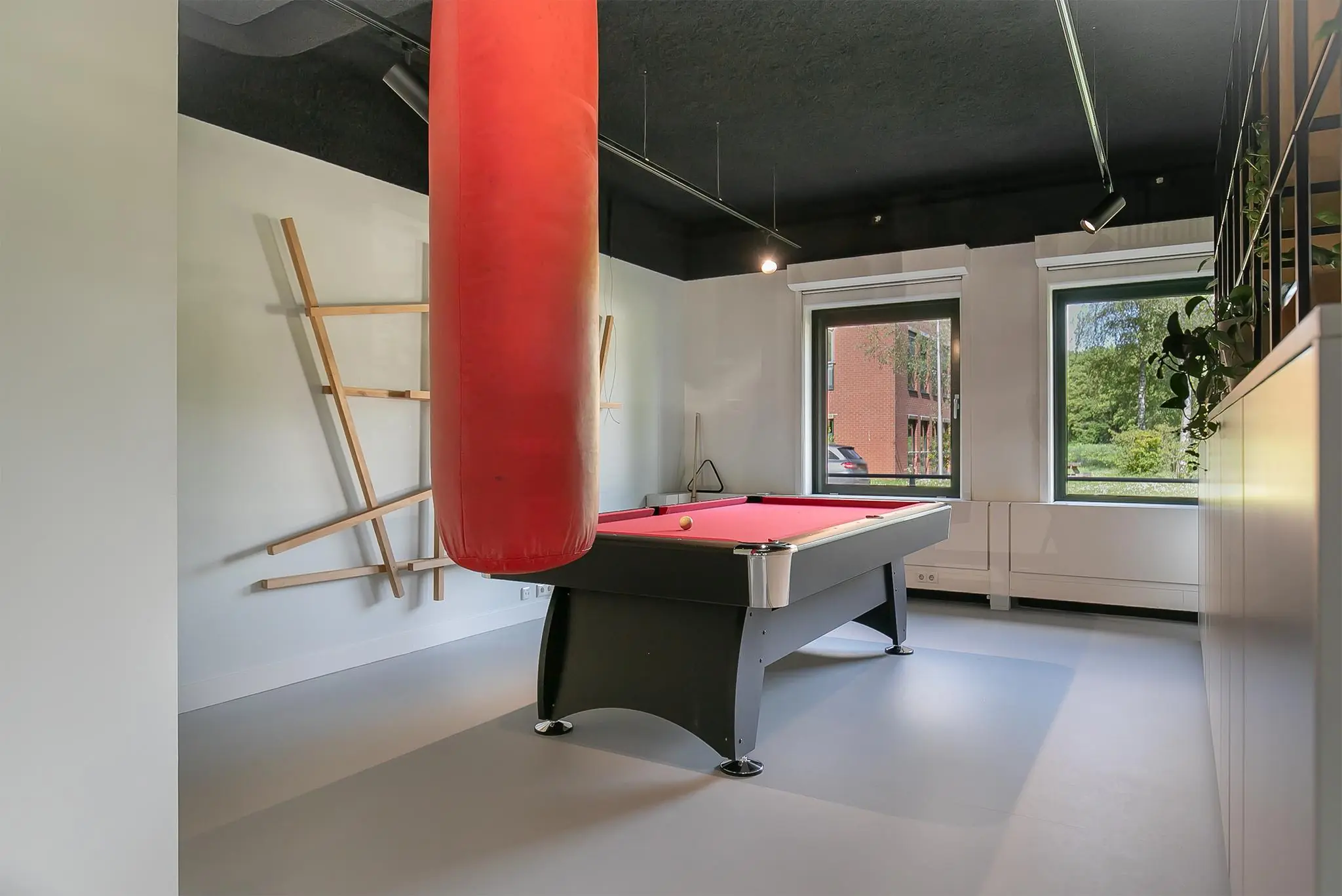 Moderne speelkamer aan de Kralingseweg met een rood biljart, bokszak en wanddecoratie.