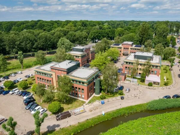 Luchtfoto van een kantoorgebouw aan de Kralingseweg in Rotterdam, omringd door groen en parkeerplaatsen.