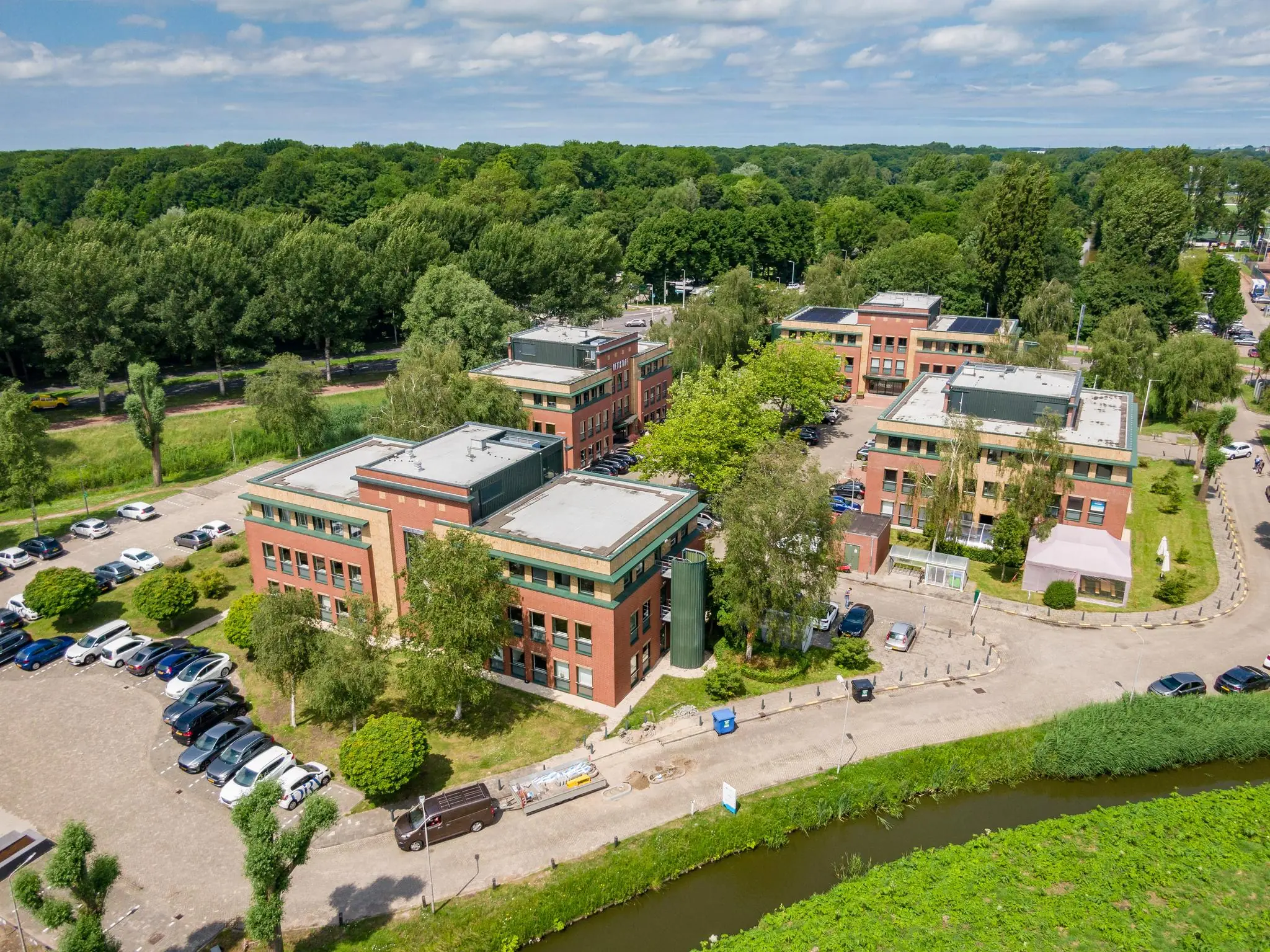 Luchtfoto van een kantoorgebouw aan de Kralingseweg in Rotterdam, omringd door groen en parkeerplaatsen.