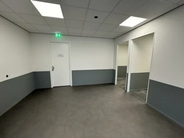 Lege en strakke gang met grijze vloer en halve wandbekleding in een gebouw aan de Coolsingel.