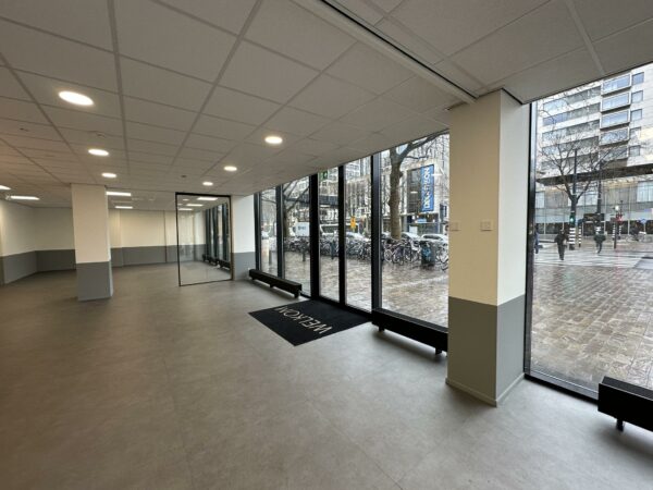 Leeg winkelpand met grote glazen ramen aan de Coolsingel in Rotterdam, uitkijkend op een drukke straat.