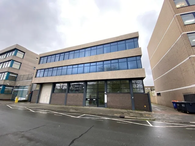 Kantoorgebouw aan de Volmerlaan met grote ramen en drie verdiepingen, gezien vanaf de straat.