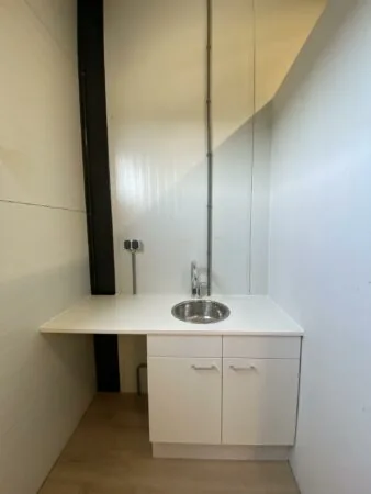 Kleine kitchenette met witte kastjes, een ronde spoelbak en een hoge kraan aan de Aalsmeerderweg.