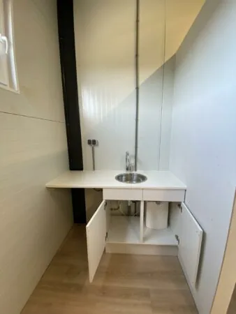 Kleine kitchenette aan de Aalsmeerderweg met een wit aanrecht, ronde spoelbak en open keukenkastjes.