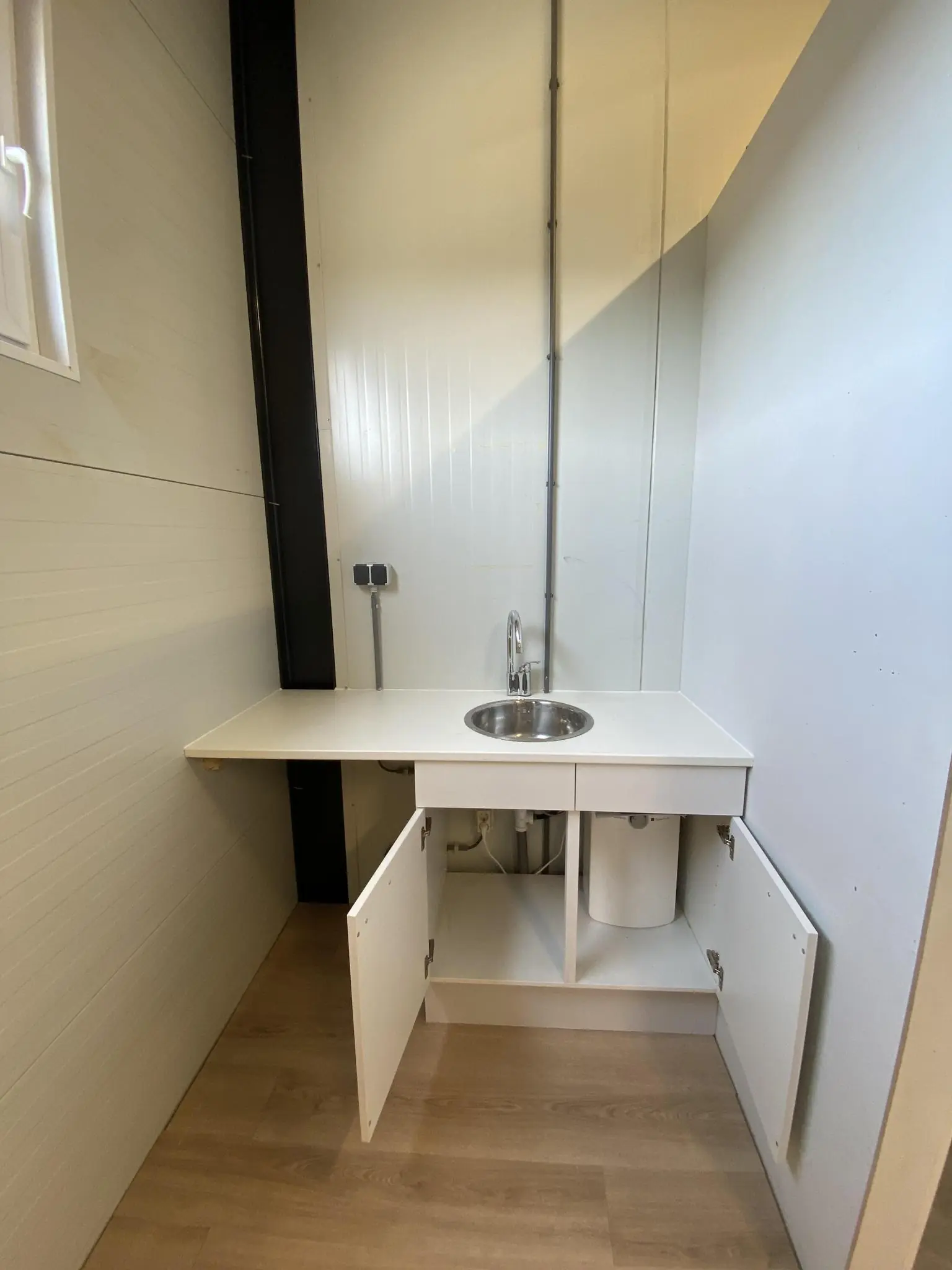 Kleine kitchenette aan de Aalsmeerderweg met een wit aanrecht, ronde spoelbak en open keukenkastjes.