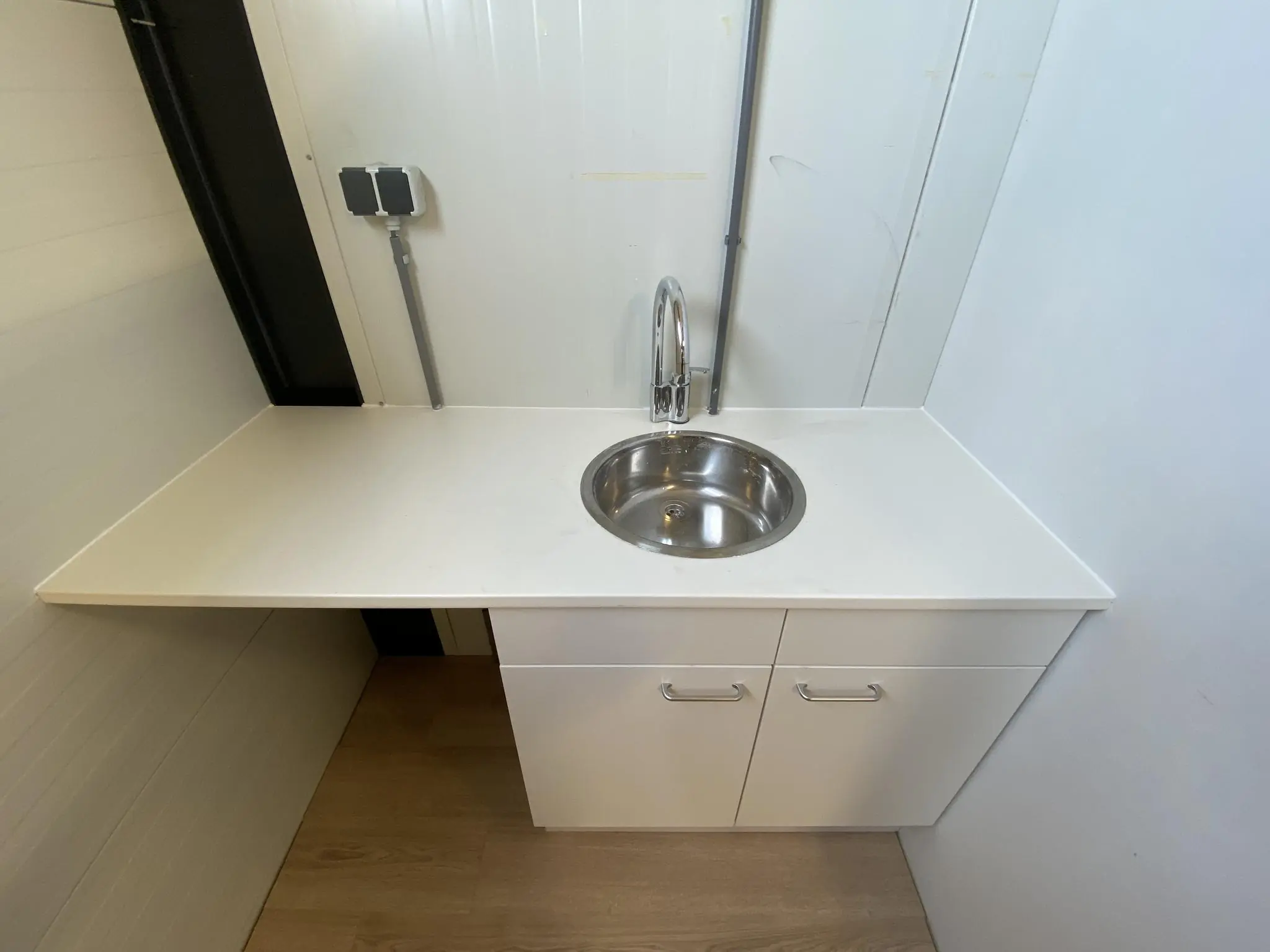 Wit aanrecht met ronde RVS wasbak en kastjes eronder, tegen een witte wand op de Aalsmeerderweg.